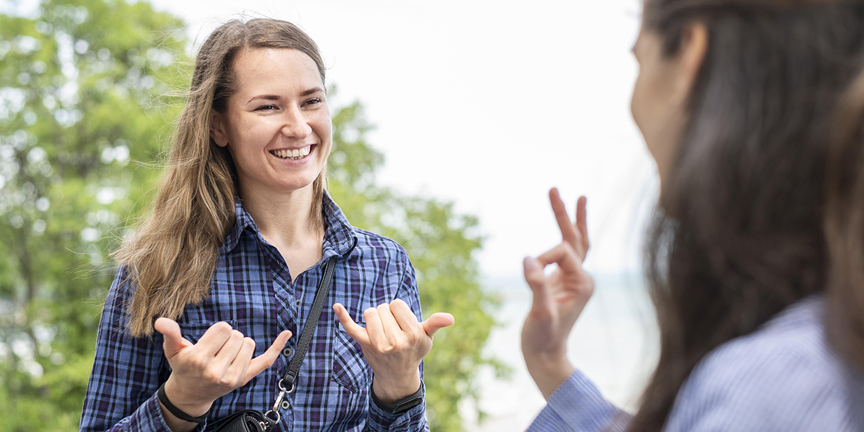 Two adult women communicating through sign language