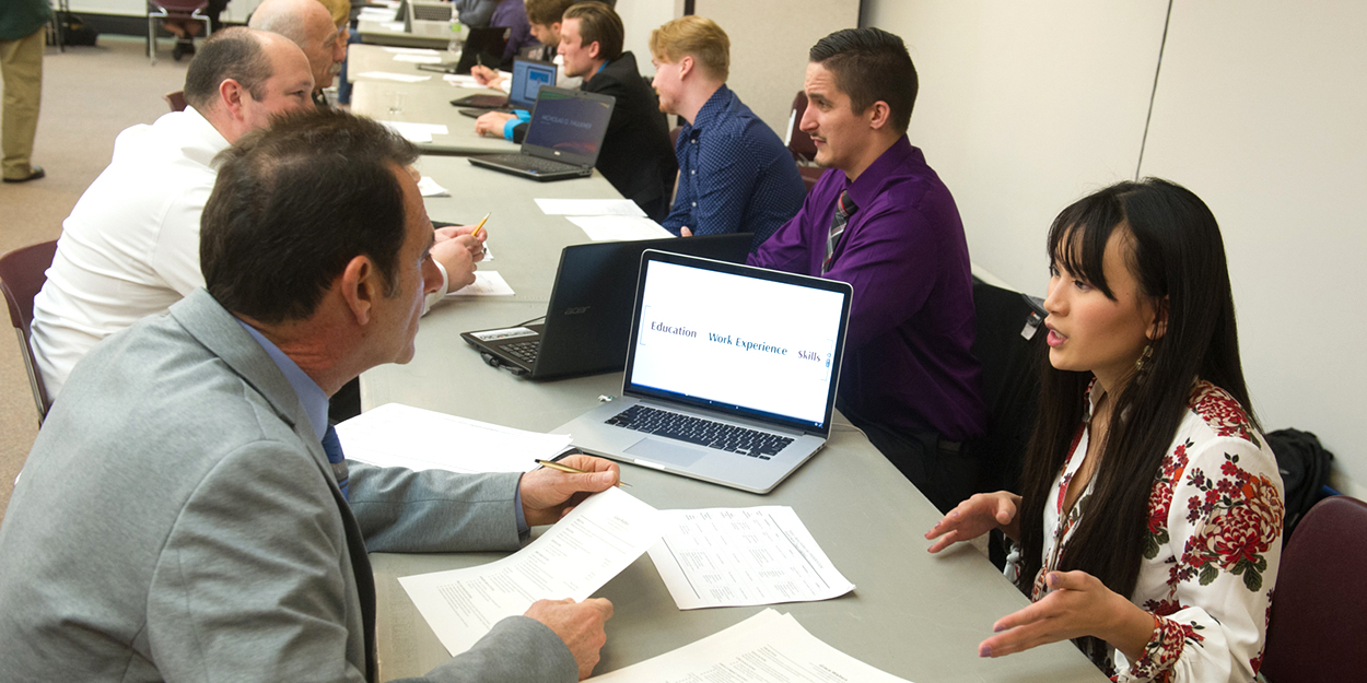 Students working at computers in a formal setting.