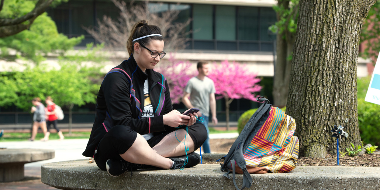 A student sitting on the Stratton Quadrangle at SIUE.