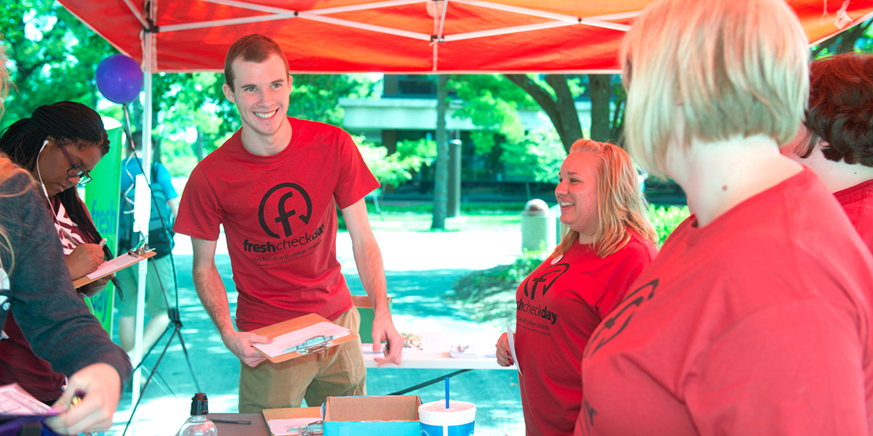 Student handing out forms on Fresh Check Day.