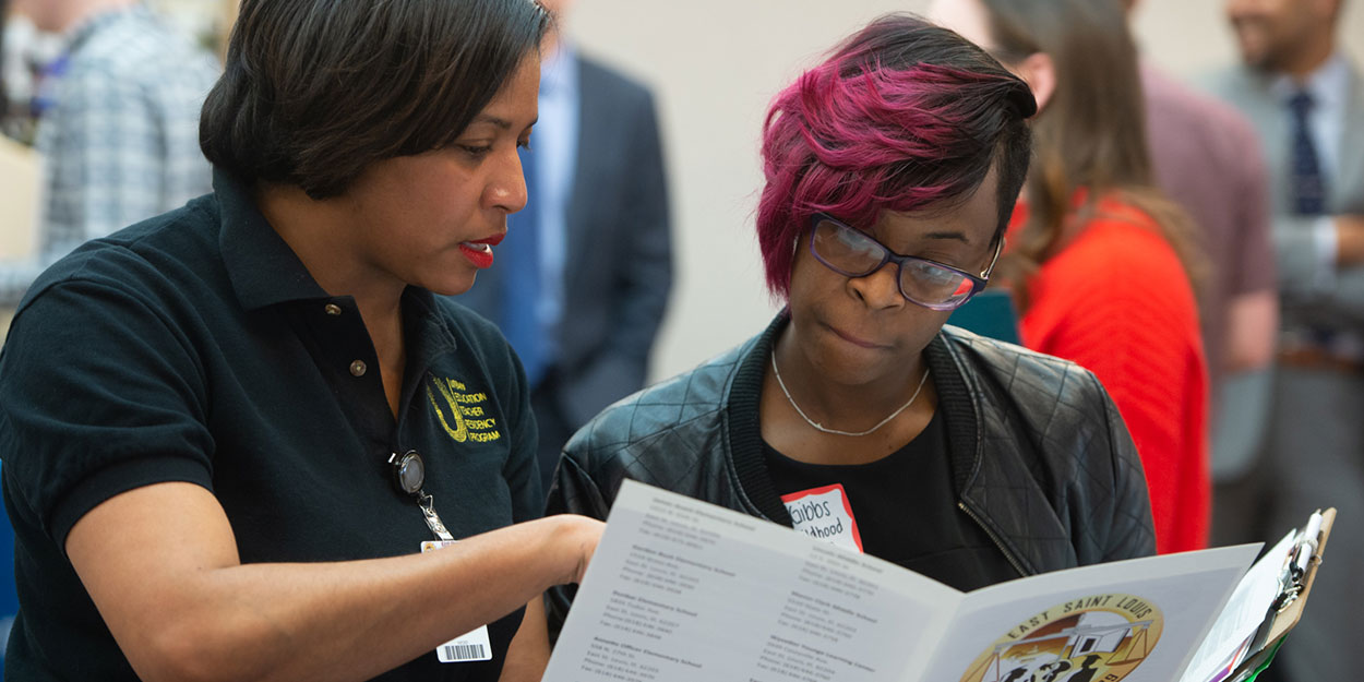 Two women discussing something while looking over a pamphlet