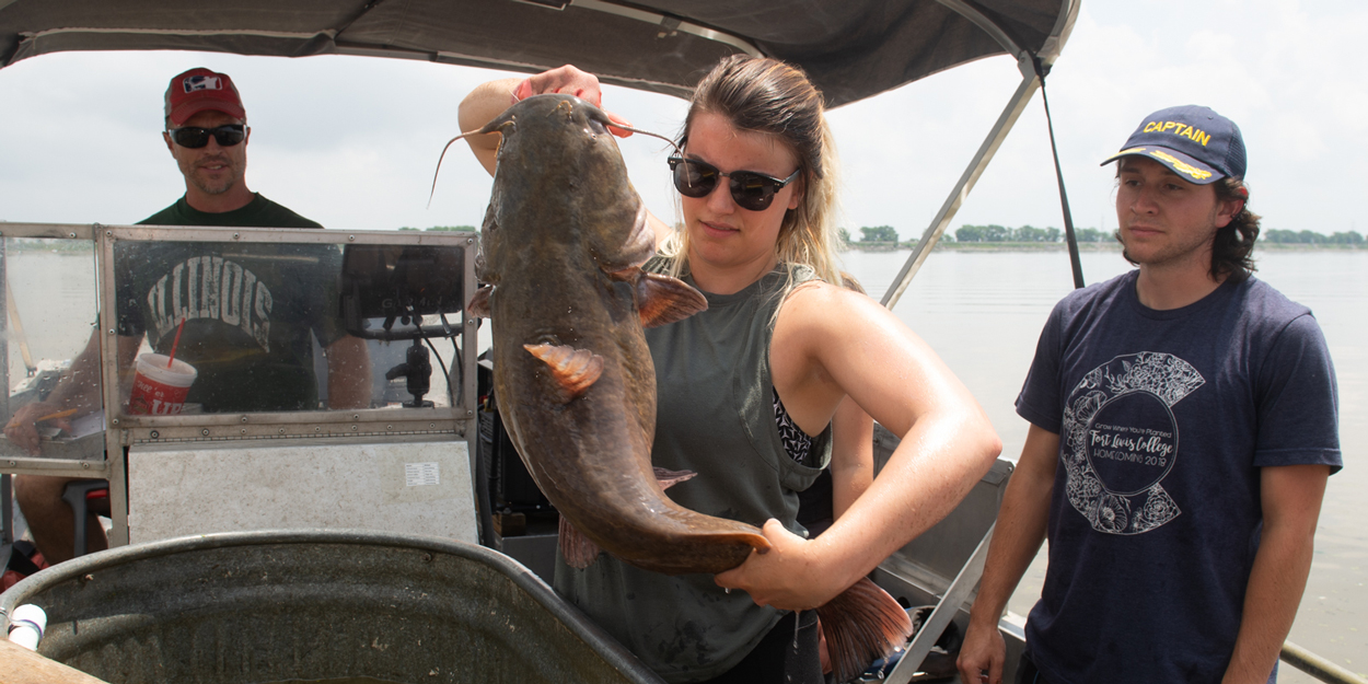 A SIUE student on a boat with a fish.