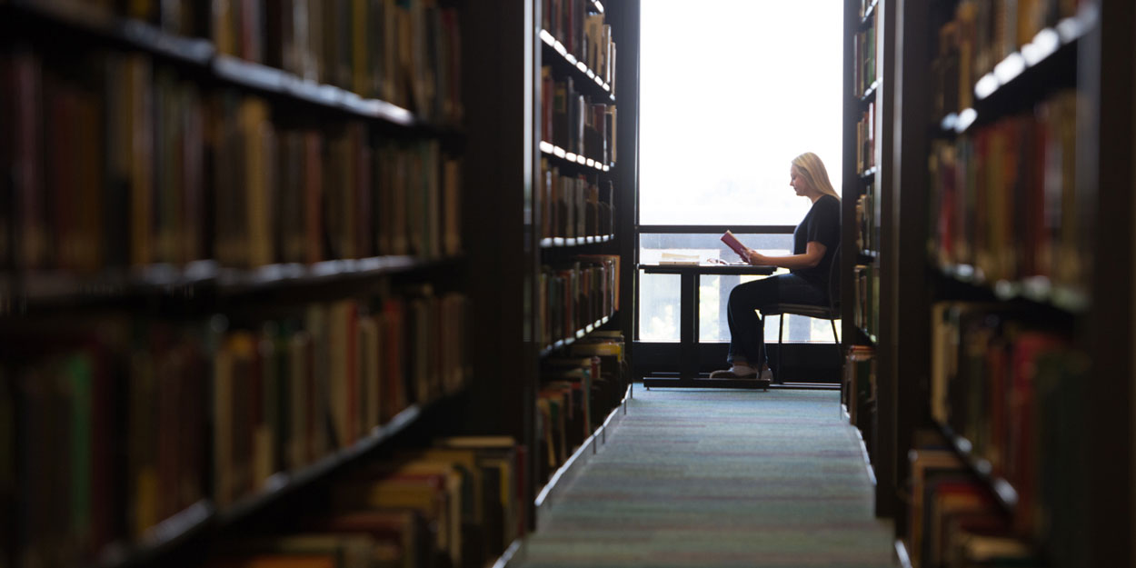 SIUE student reading near a window in the Lovejoy Library.