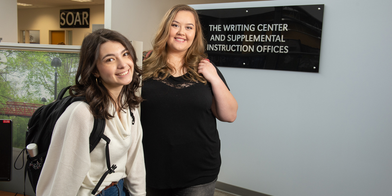 Two student in front of the Writing Center at SIUE.