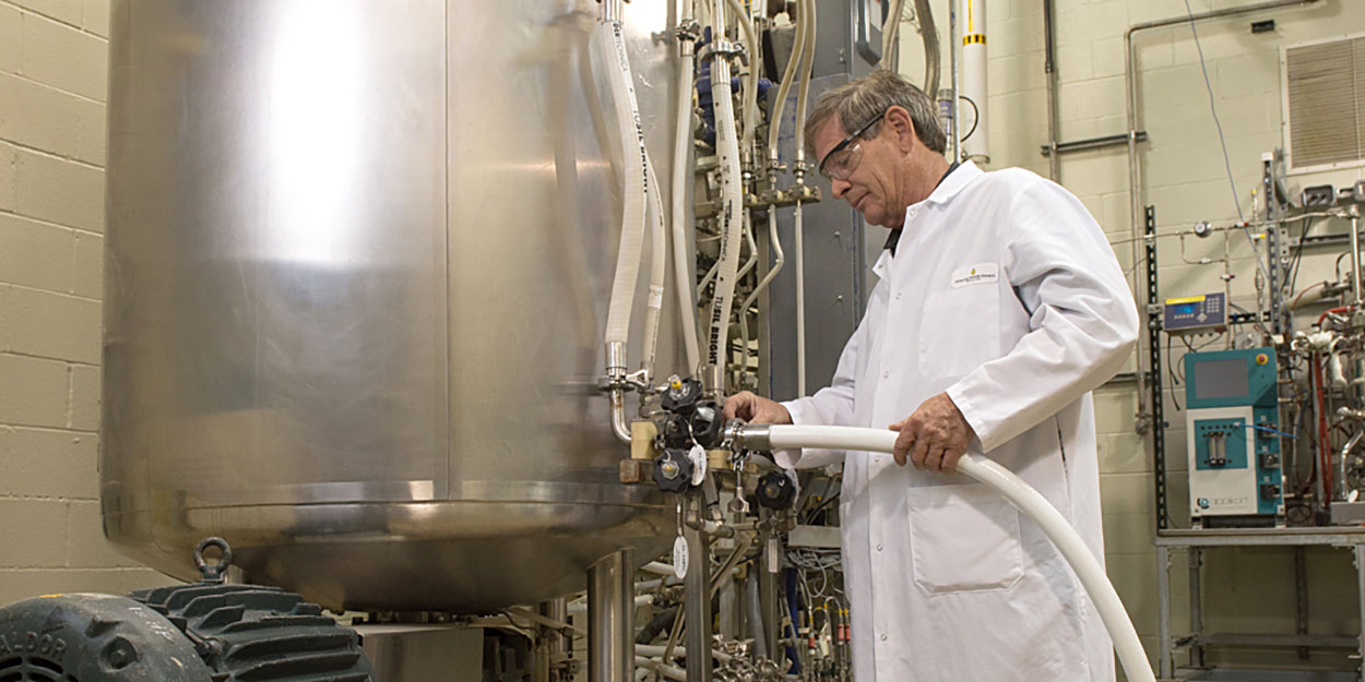 A NCERC worker, in proper protective gear, working with a fermentation machine