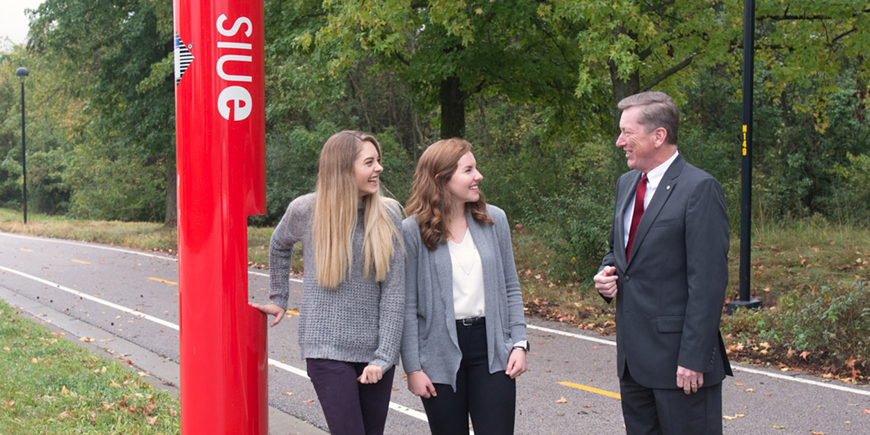 Two Students talking to former Vice Chancellor at SIUE Rich Walker on the SIUE bike path.