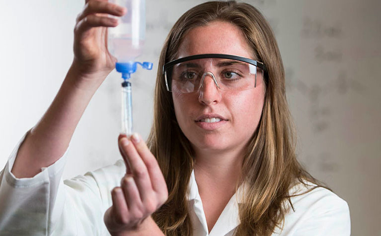 A sutdent at SIUE School of Pharmacy drawing liquid from a container using a syringe