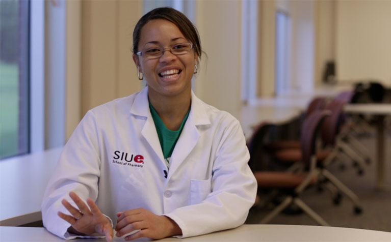 A student of the SIUE School of Pharmacy sitting at a table smiling