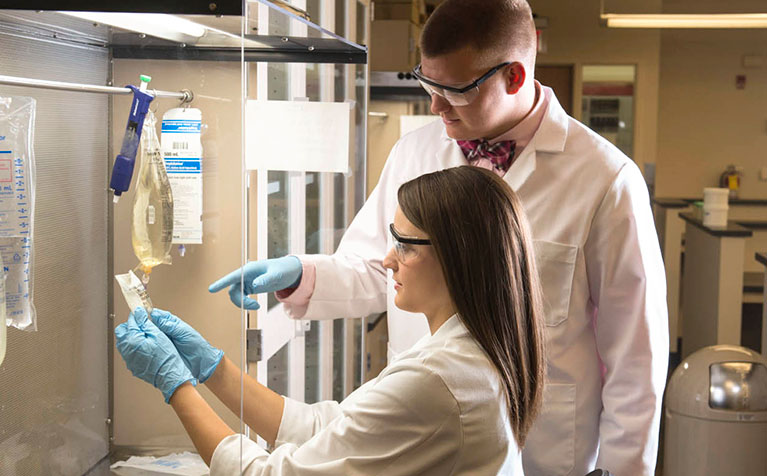 A student and instructor of SIUE School of Pharmacy illustrating the proper method of dealing with IV bags