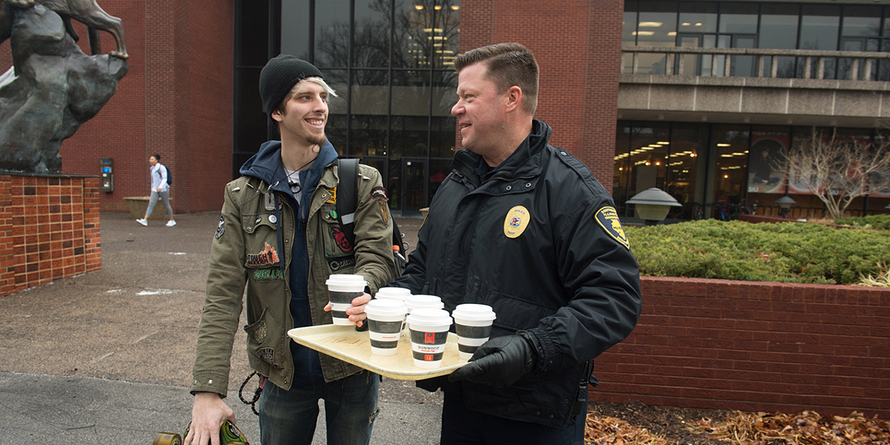 The chief of Police at SIUE giving hot chocolate to a student.