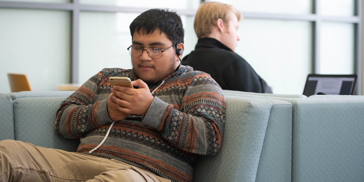 A student looking at his phone in the Student Success Center.