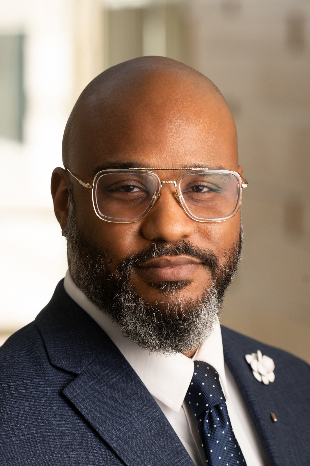 A smiling man with eyeglasses, a shaved head, and a bearded chin