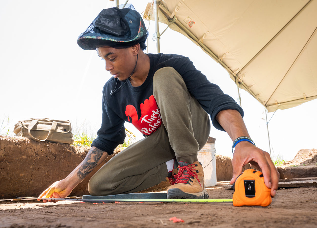 An Archaeology student using an instrument for measurement