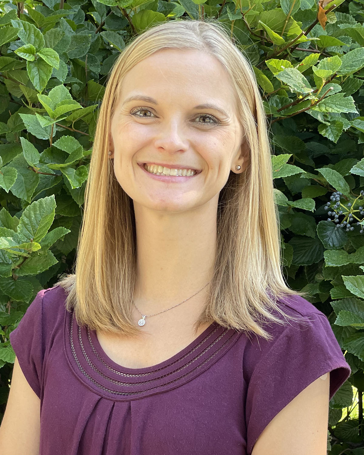 Sarah Laux Headshot (outside with greenery in background)