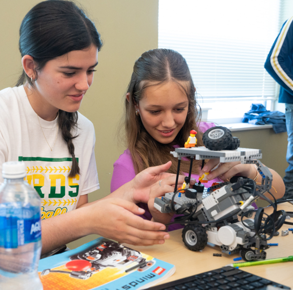 Two young students holding and examining small model car