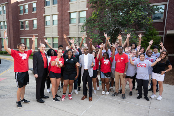 Drs Mahony and Minor with students with their hands up in front of residence hall