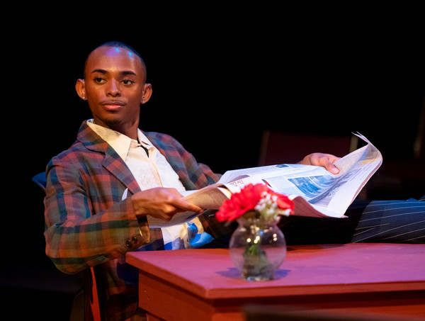 Trey leans back in chair with newspaper