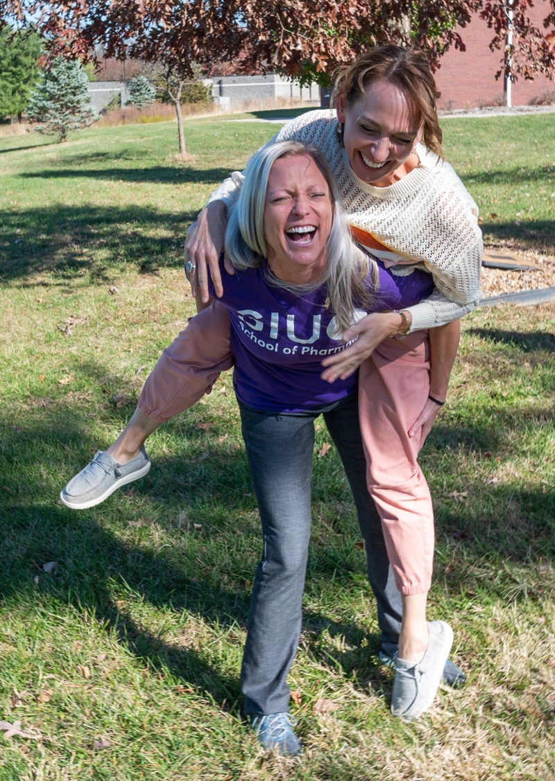 Faculty jumping on each other for fun outside