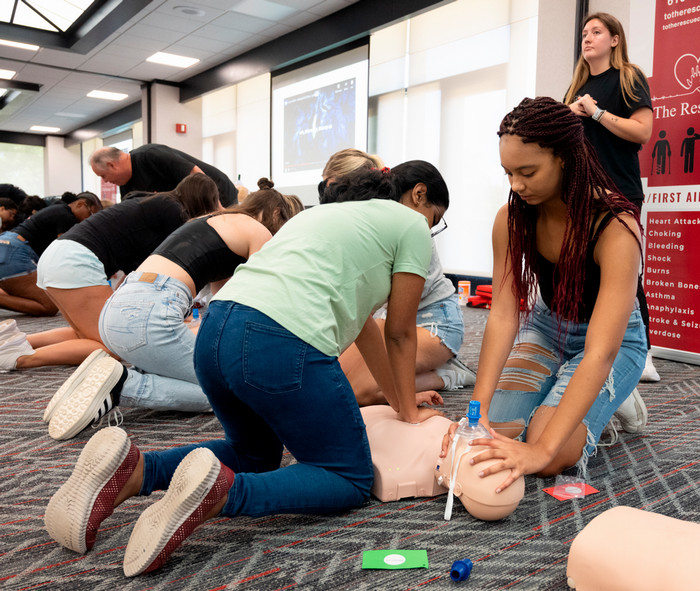 girls practicing chest compressions on a mannequin