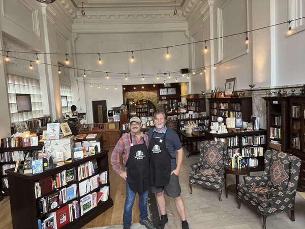 Two bookstore owners standing in the middle of room with rows of bookshelves