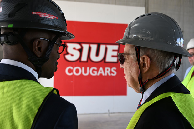 Chancellor Minor and Rep Dick Durbin stand in front of wall that reads SIUE Cougars the two men are facing the wall