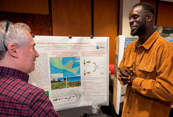 Student presents research on poster to professor