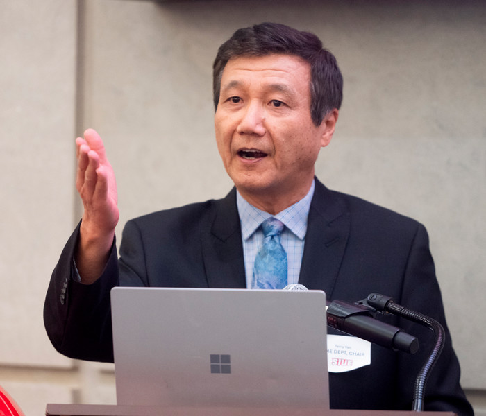 terry yan speaking at a podium inside the atrium of the engineering building